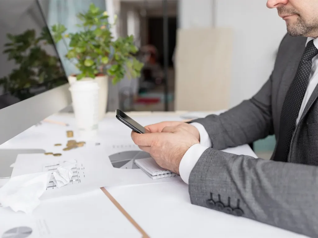 usinessman using a smartphone to research how to choose the right strata manager.